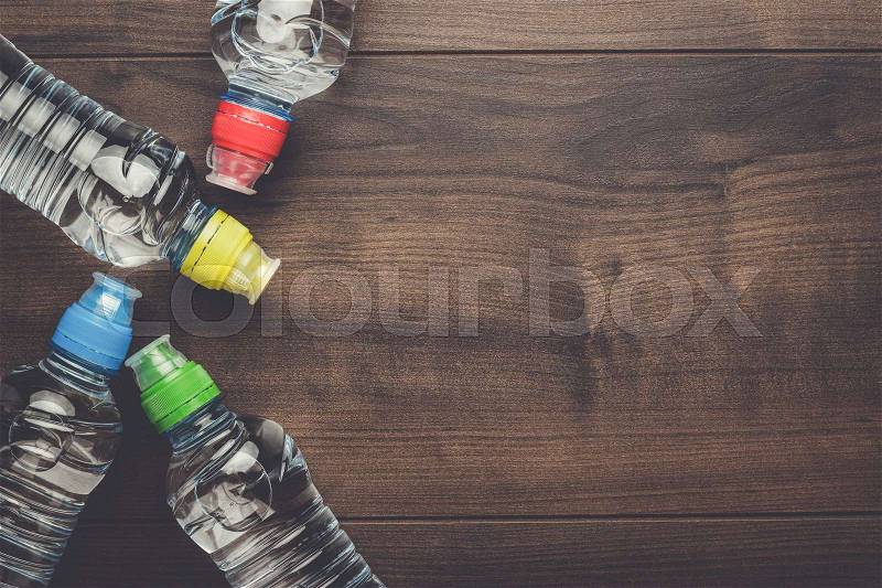 Plastic water bottles with caps of different colour on the wooden table, stock photo
