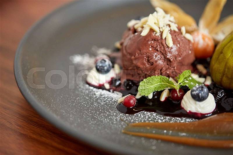 Food, new nordic cuisine and sweets concept - close up of chocolate ice cream dessert with blueberry kissel, honey baked fig and greek yoghurt on plate at restaurant, stock photo