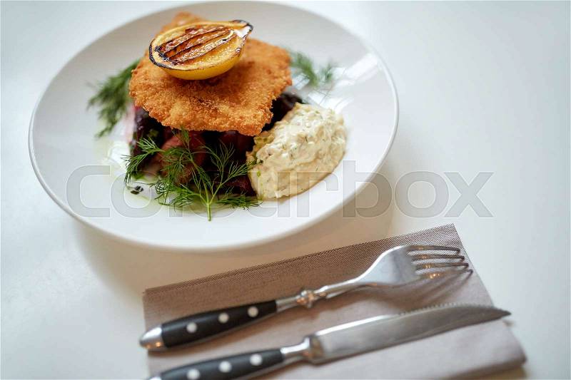 Food, new nordic cuisine, dinner, culinary and cooking concept - close up of breaded fish fillet with tartar sauce and oven-baked beetroot tomato salad on plate, stock photo