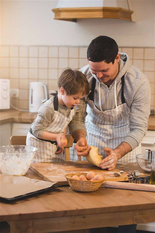 Father and his son preparing bisquits in the kitchen, stock photo