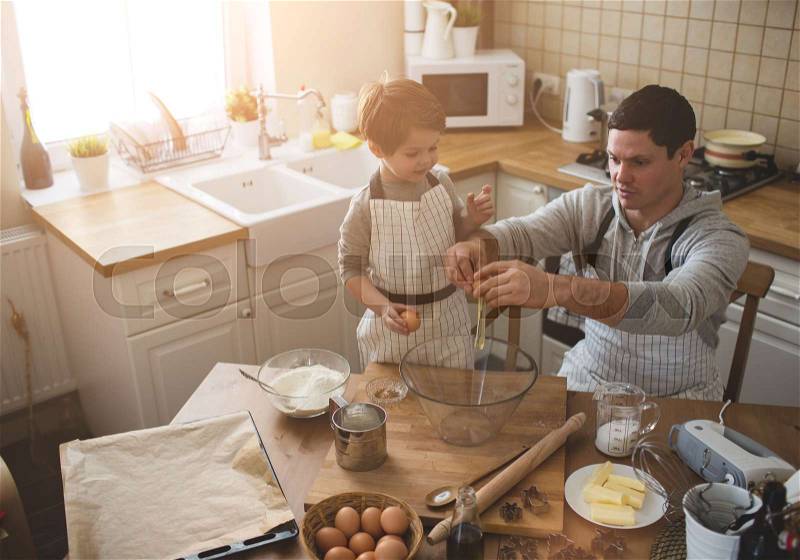 Father and his son preparing bisquits in the kitchen, stock photo
