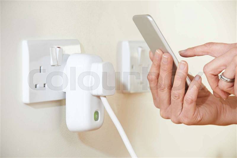 Woman Controlling Smart Plug Using App On Mobile Phone, stock photo