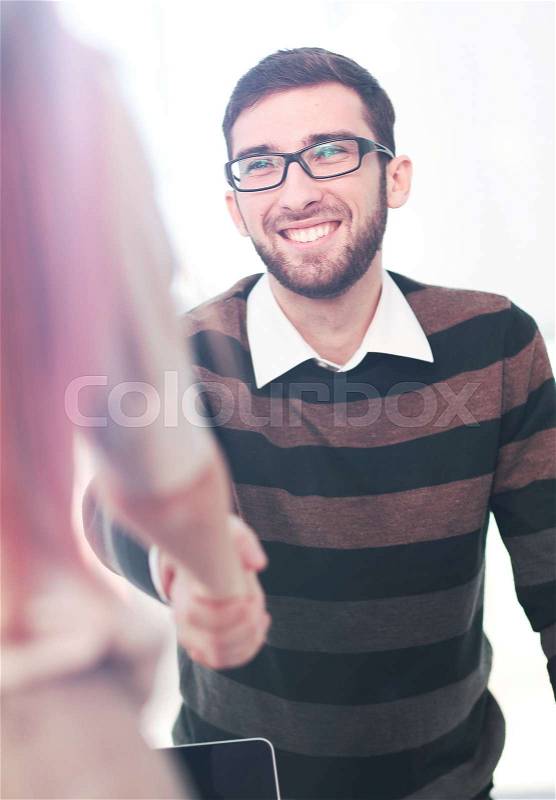 Manager greeting new employee and smiling in office, stock photo