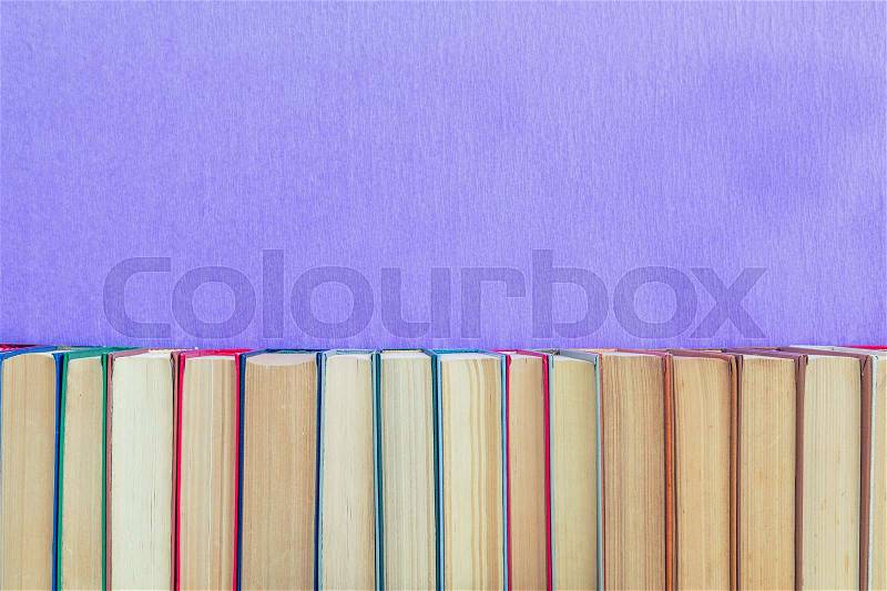 Books background. Many different books on violet wall, stock photo