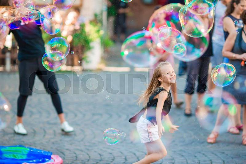 Adorable little girl blowing soap bubbles in Trastevere in Rome. Happy kid enjoy summer vacation in Italy, stock photo