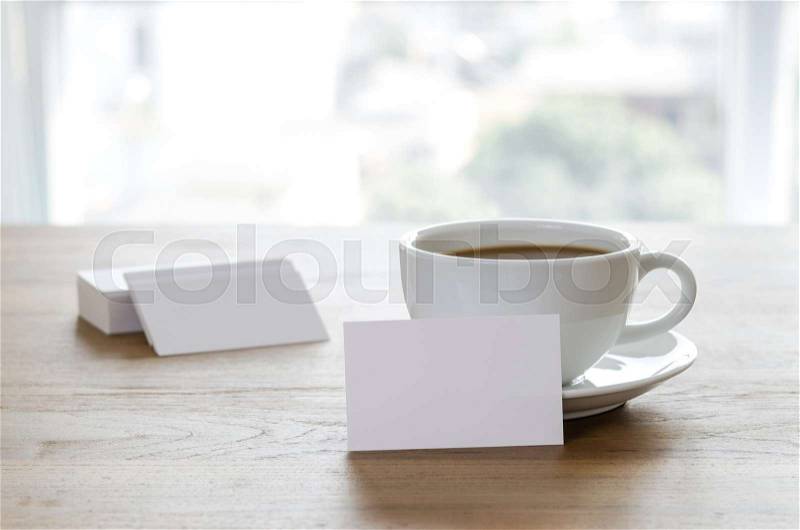 Blank business cards and cup of coffee on wooden table. Corporate stationary branding mock up, stock photo
