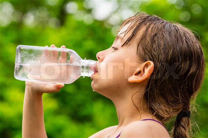 Closeup of young girl drinking fresh cold tap water from transparent plastic drinking bottle while outdoors on a hot summer day, stock photo