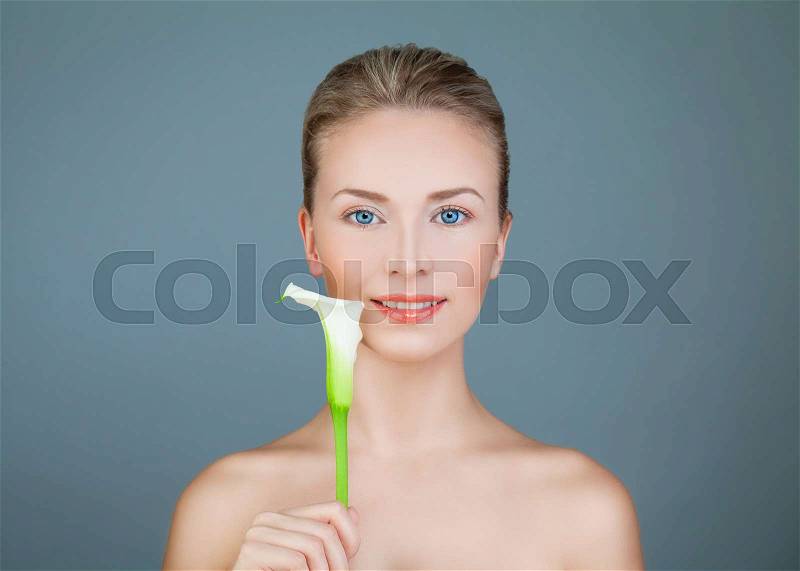 Natural Beauty. Healthy Woman with Lily Flower Smiling on Blue Background, stock photo