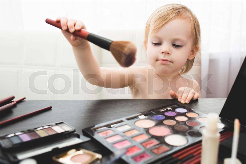 Cute little girl with brush doing make up, stock photo