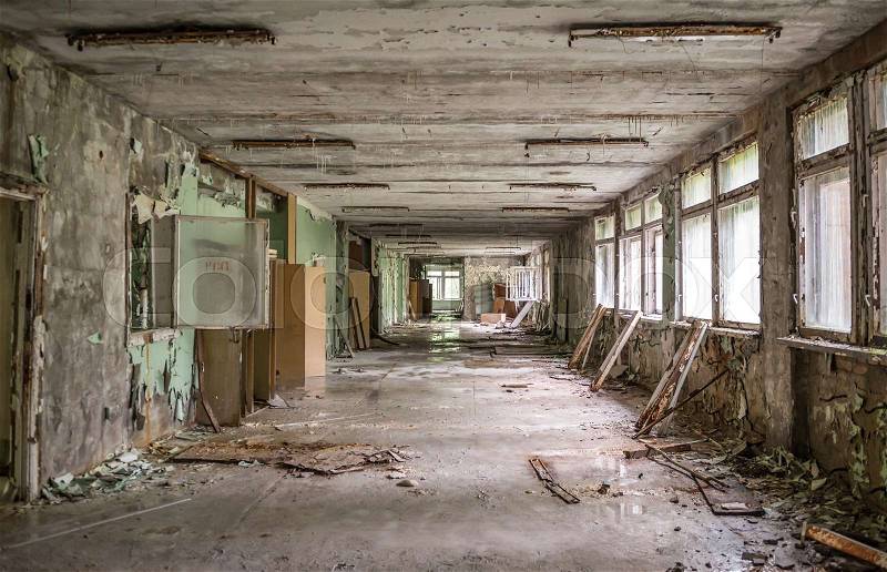 Gloomy abandoned school corridor with debris and broken windows and doors in Pripyat, stock photo
