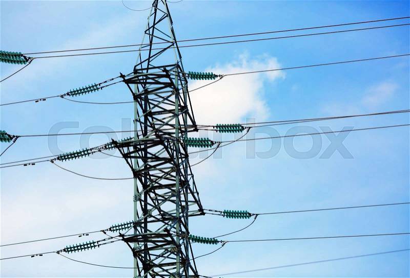 High voltage post. Electricity transmission pylon silhouetted against blue sky, stock photo