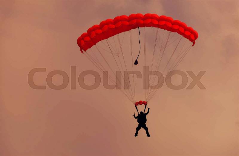 Male parachutist makes the jump from the plane on a red parachute, stock photo