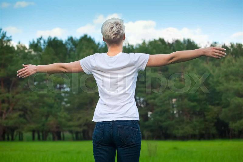 Attractive young blonde girl with outstretched hands in the hand of a beautiful cloudy sky, stock photo