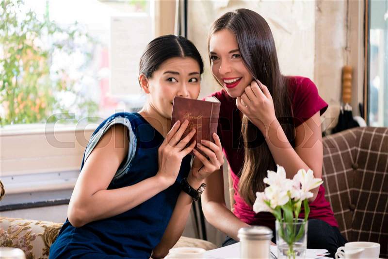 Young woman whispering gossip or sharing a secret with her best friend, stock photo