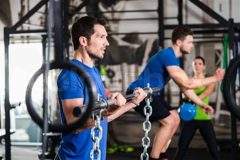 Man lifting dumbbell and chain in functional training gym session , stock photo