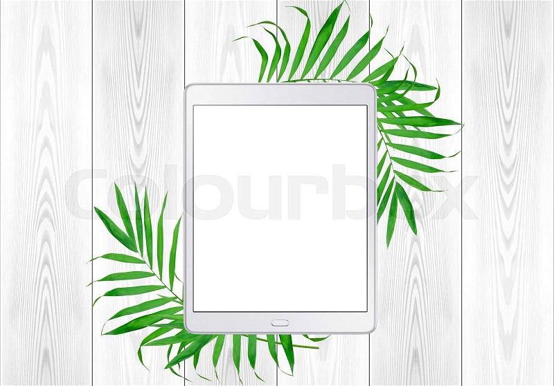 Tablet pc in green fern leaves frame on white wood table. Top View, stock photo