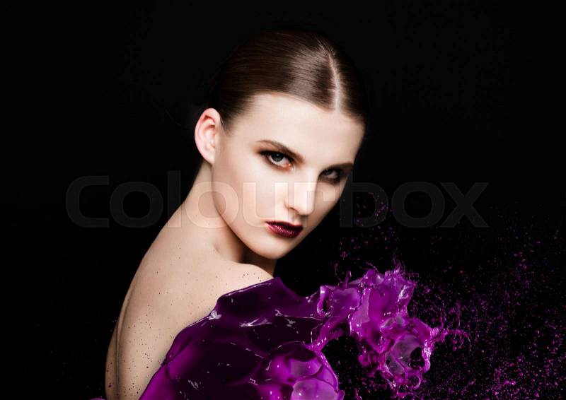 Purple paint splash over beauty makeup model girl abstract on black background, stock photo