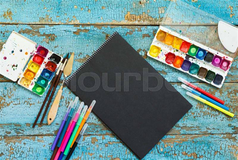 Art of Painting. Painting set: brushes, paints, crayons, watercolor, black paper on a blue wooden background, stock photo