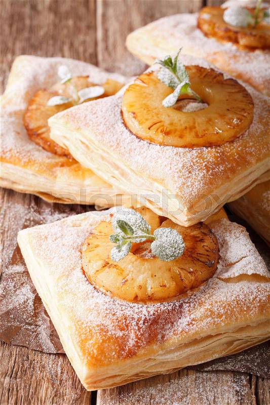 Puff pastry cake with pineapple, decorated with mint and powdered sugar close-up on the table. vertical , stock photo