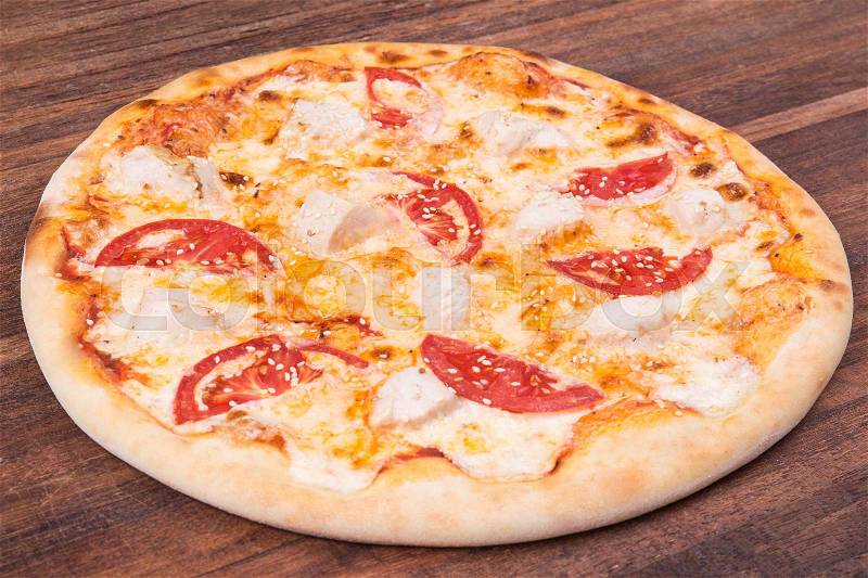 Hot pizza slice with melting cheese on a rustic wooden table, stock photo