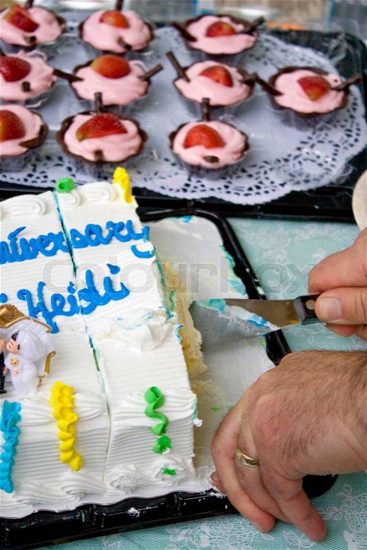 Cutting some anniversary cake with mousse cups in the background, stock photo