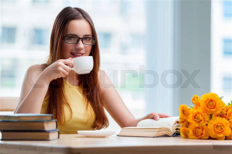 Young student drinking coffee while sudying, stock photo