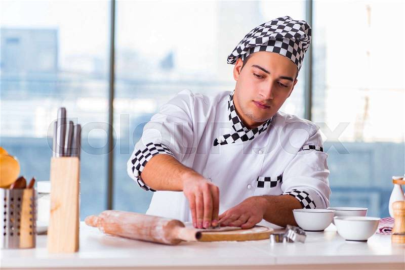 Young man cooking cookies in kitchen, stock photo