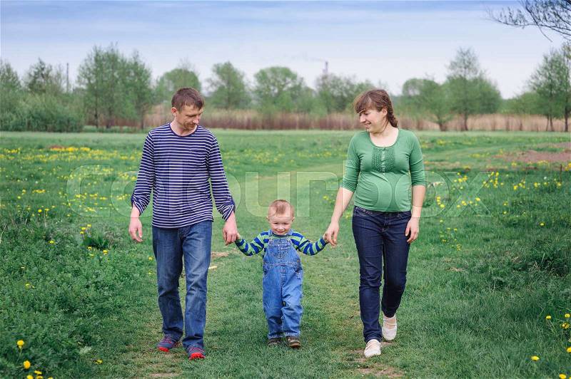 Young family and young son walk on a spring meadow, stock photo