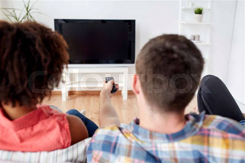 Friendship, people and entertainment concept - happy friends with remote watching tv at home, stock photo