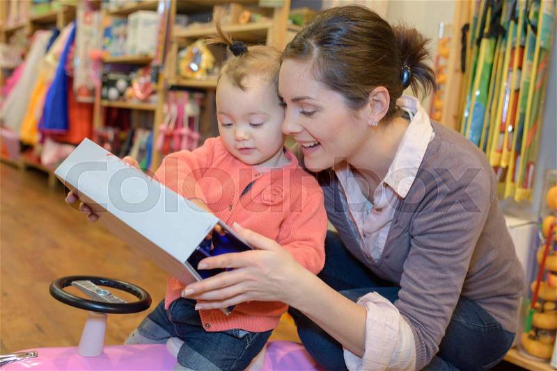 Young mother her daughter shopping at the toy store, stock photo