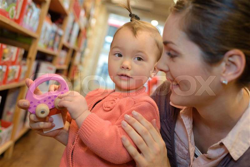 Young mother her daughter shopping at the toy store, stock photo