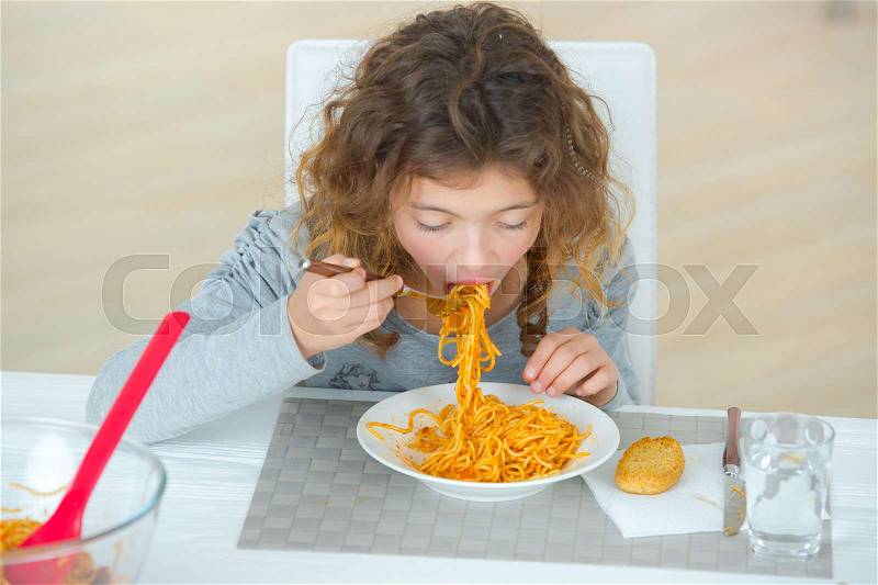 Kid eating spaghetti, stock photo