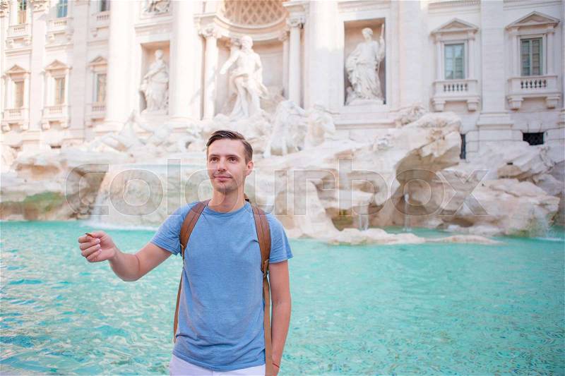 Happy man trowing coins at Trevi Fountain, Rome, Italy for good luck. Caucasian guy making a wish to come back, stock photo