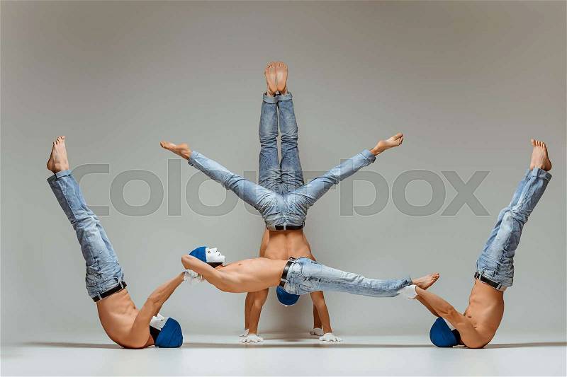 The group of gymnastic acrobatic caucasian men posing in balance posture on gray studio background in hats and masks, stock photo