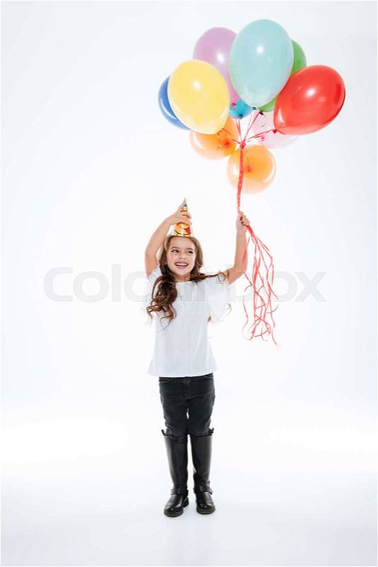 Cheerful girl in birthday hat with balloons standing and laughing, stock photo