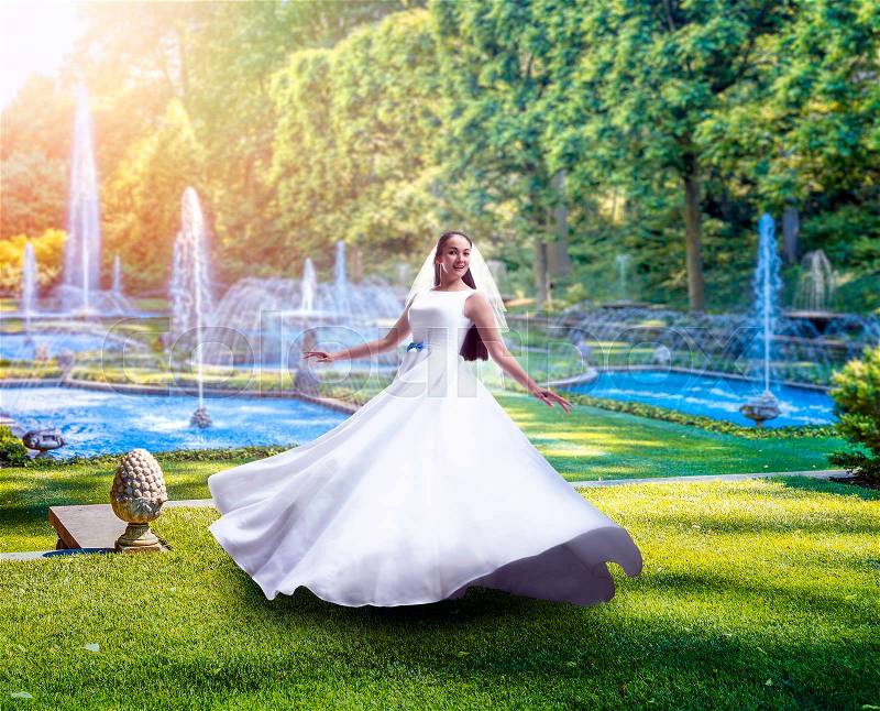Young bride in white dress, green park with fountains on background, stock photo