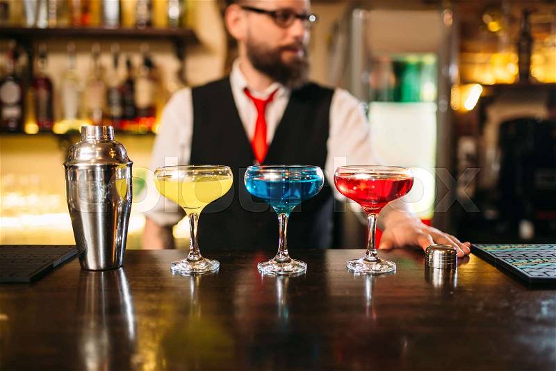 Bartender behind bar counter show alcohol coctails in restaurant, stock photo