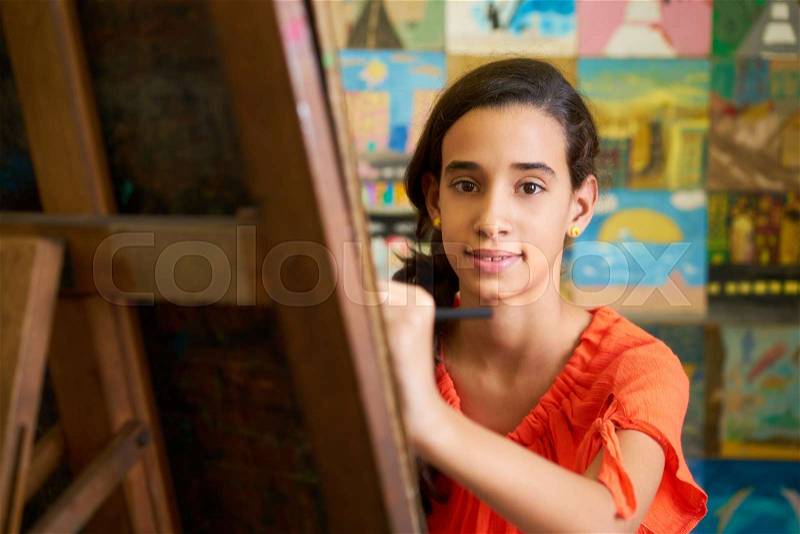School of art, college of arts. Portrait of happy hispanic girl smiling, learning to paint and looking at camera, stock photo