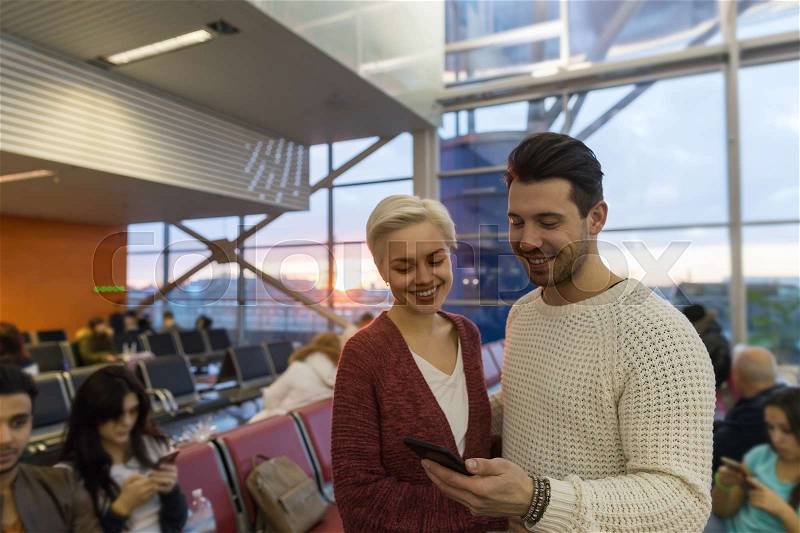 Young Couple In Airport Lounge Waiting Departure Happy Smile Man And Woman Use Cell Smart Phone, Flight Delay, stock photo