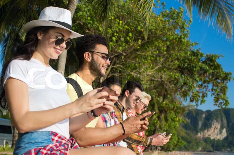 Young People Group Using Cell Smart Phones Tropical Park Palm Trees Friends Chatting Online Holiday Sea Summer Vacation Ocean Travel, stock photo