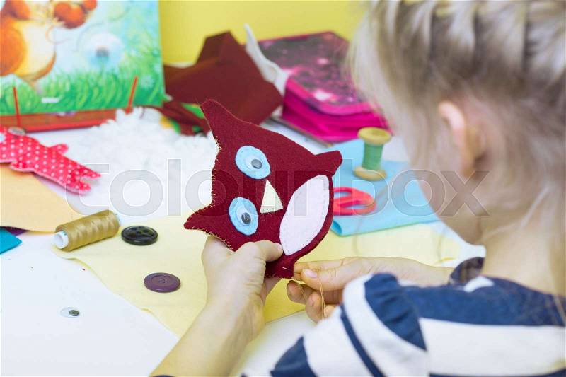 Creation. little girl sews toy made of felt , stock photo