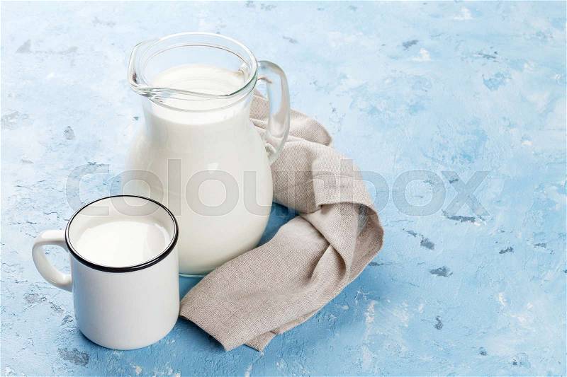 Milk jug and cup on stone table. Dairy products. View with copy space, stock photo