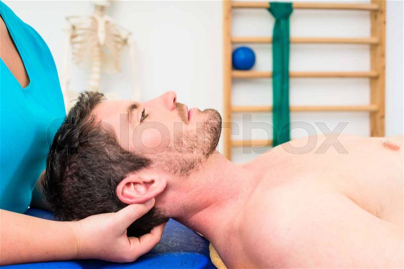 Physiotherapist woman treating young bare-chested man on couch, stock photo