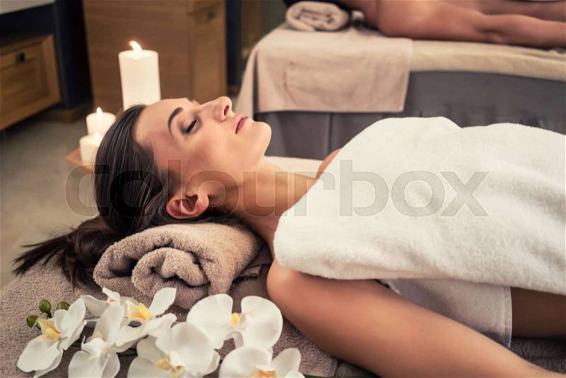 Young man and woman lying down on massage beds at Asian luxury spa and wellness center, stock photo