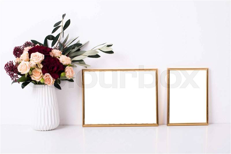 Two golden frames mock-up on white wall background, home decor with flowers, stock photo