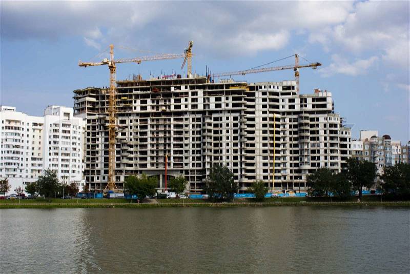 Apartment building under construction over waters under blue skies, stock photo