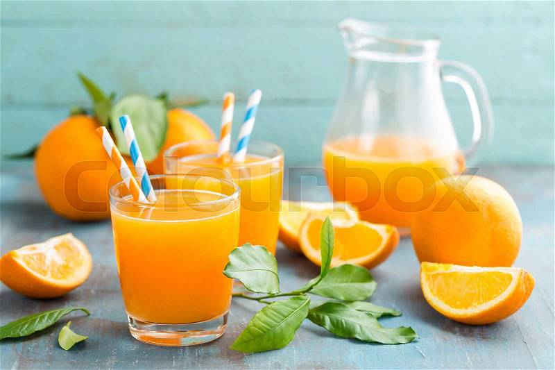 Orange juice in glass and fresh fruits with leaves on wooden background, vitamin drink or cocktail, stock photo