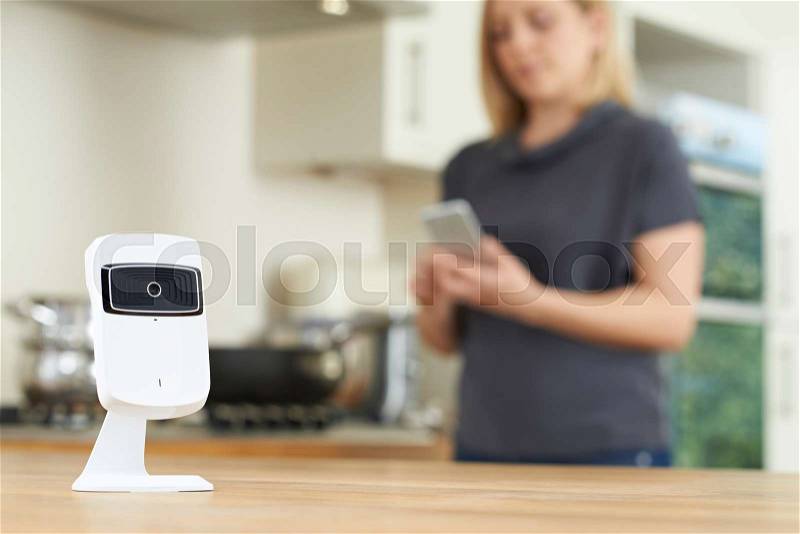 Woman Controlling Smart Security Camera Using App On Mobile Phone, stock photo