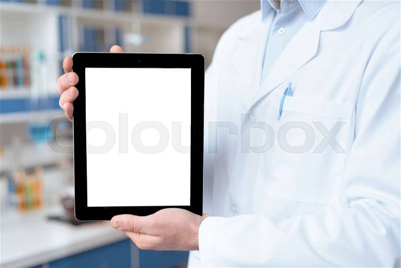 Close-up partial view of doctor in lab coat showing digital tablet with blank screen, stock photo