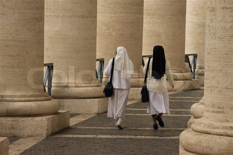 The two nuns in different costumes are walking along obelisks in the neighbourhood of the St. Peter\'s Square in the city Rome in the summer, stock photo